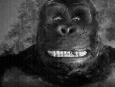 A Close Up Of A Gorilla 'S Face With A Smile On It 'S Face In A Black And White Photo . GIF