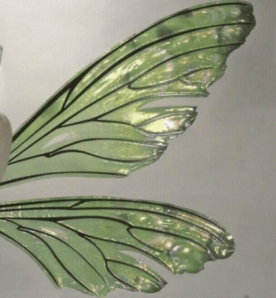 A Close Up Of A Green Fairy Wing On A White Surface GIF