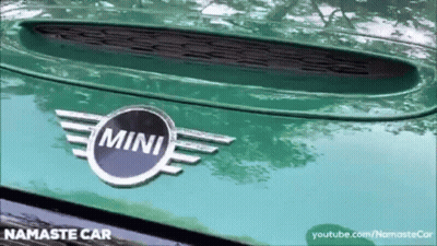 A Close Up Of A Green Mini Car With A Namaste Car Logo GIF