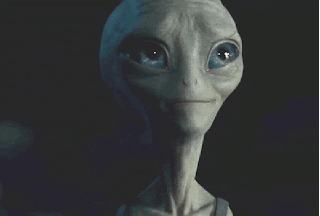 A Close Up Of A Grey Alien 'S Face With Blue Eyes GIF