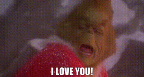 A Close Up Of A Grinch Holding A Heart And Saying `` I Love You '' . GIF