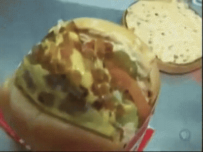 A Close Up Of A Hamburger With A Bunch Of Toppings GIF
