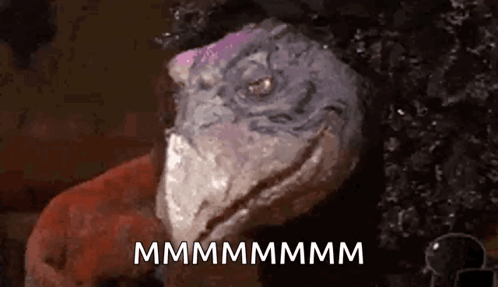 A Close Up Of A Lizard 'S Face With The Words `` Mmmmmm '' Written On It . GIF