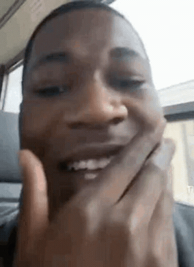 A Close Up Of A Man Covering His Mouth With His Hands While Smiling . GIF