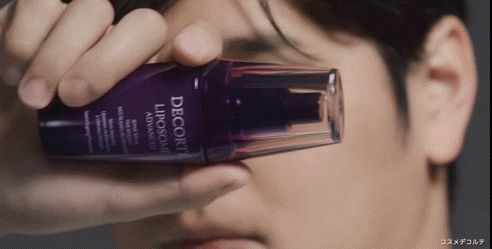 A Close Up Of A Man Holding A Bottle Of Decorte Liposome Advanced GIF