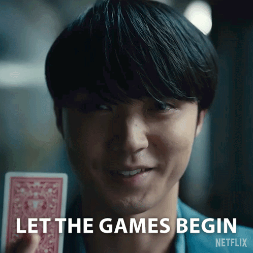 A Close Up Of A Man Holding A Playing Card With The Words Let The Games Begin Netflix Written On The Bottom GIF