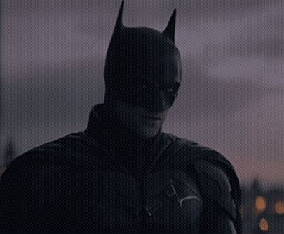A Close Up Of A Man In A Batman Costume Looking At The Camera GIF