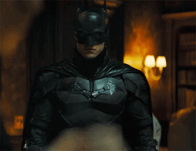 A Close Up Of A Man In A Batman Suit And Mask Standing In A Room . GIF