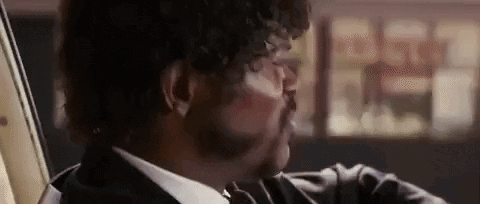 A Close Up Of A Man In A Suit And Tie Holding A Gun . GIF