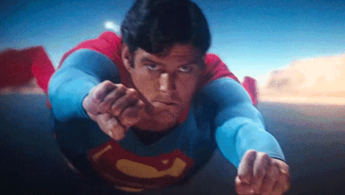 A Close Up Of A Man In A Superman Costume Flying In The Air . GIF