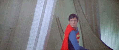 A Close Up Of A Man In A Superman Costume Flying Through The Air . GIF