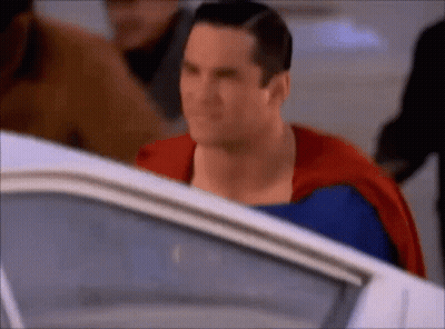 A Close Up Of A Man In A Superman Costume Standing Next To A White Car . GIF
