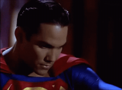 A Close Up Of A Man In A Superman Costume With A Red Cape . GIF