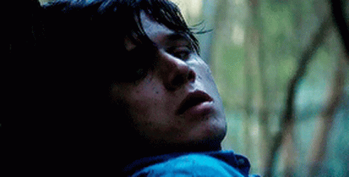 A Close Up Of A Man Laying Down In The Woods With His Eyes Closed . GIF