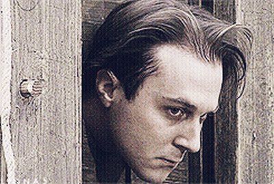 A Close Up Of A Man 'S Face Against A Wooden Fence GIF