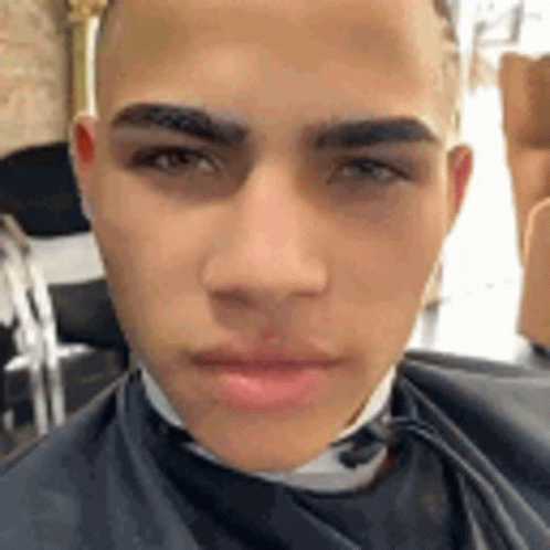 A Close Up Of A Man 'S Face In A Barber Shop With A Cape On . GIF