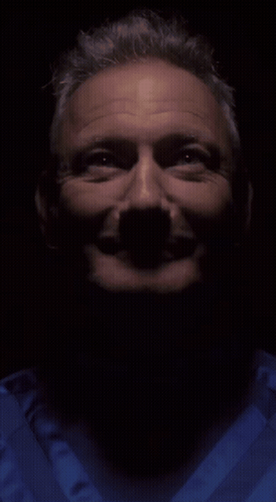 A Close Up Of A Man 'S Face In A Dark Room GIF