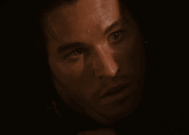 A Close Up Of A Man 'S Face In A Dark Room Looking At The Camera GIF