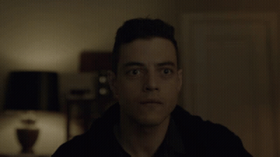A Close Up Of A Man 'S Face In A Dark Room With A Lamp In The Background GIF