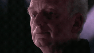 A Close Up Of A Man 'S Face In A Dark Room With A Purple Light Behind Him . GIF