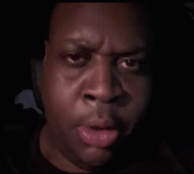 A Close Up Of A Man 'S Face In A Dark Room With His Hand On His Face . GIF