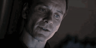 A Close Up Of A Man 'S Face In A Dark Room With Smoke Coming Out Of His Mouth . GIF