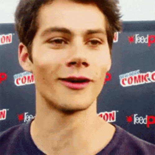 A Close Up Of A Man 'S Face In Front Of A Comic Con Sign . GIF