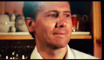 A Close Up Of A Man 'S Face In Front Of A Shelf Full Of Coffee Cups GIF