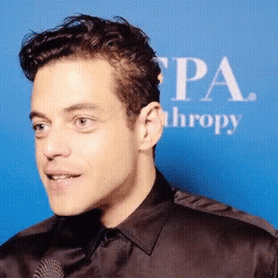 A Close Up Of A Man 'S Face In Front Of A Sign That Says Pa Thropy GIF