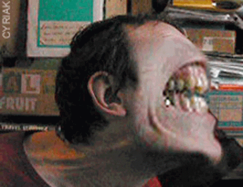 A Close Up Of A Man 'S Face In Front Of A Stack Of Fruit Boxes GIF