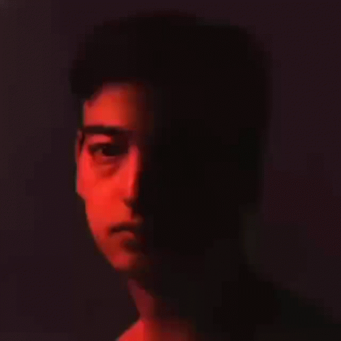 A Close Up Of A Man 'S Face In The Dark With A Red Light Shining On It . GIF