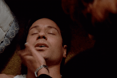 A Close Up Of A Man 'S Face Laying On A Bed GIF