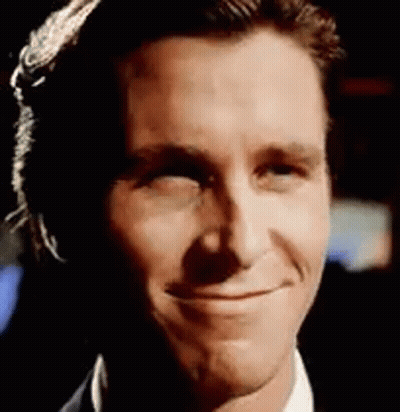 A Close Up Of A Man 'S Face Smiling While Wearing A Suit And Tie . GIF