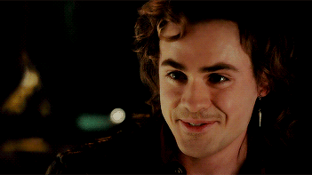 A Close Up Of A Man 'S Face Smiling With A Piercing In His Ear GIF
