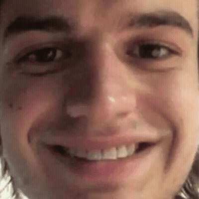 A Close Up Of A Man 'S Face Smiling With His Mouth Open . GIF