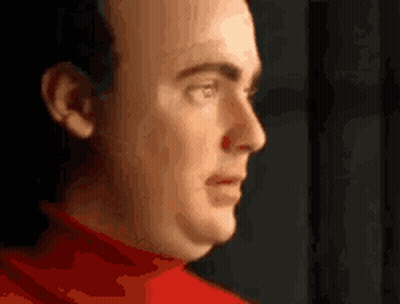 A Close Up Of A Man 'S Face Wearing A Red Sweater . GIF