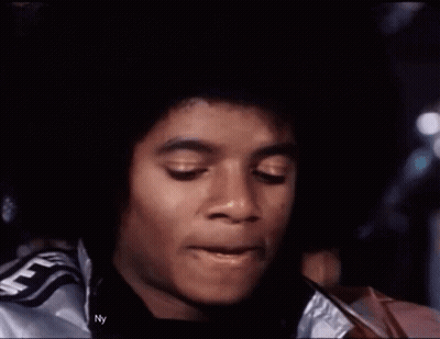 A Close Up Of A Man 'S Face Wearing A Silver Jacket With The Word Supreme On It . GIF