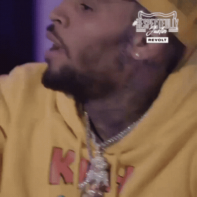 A Close Up Of A Man 'S Face Wearing A Yellow Hoodie And A Necklace . GIF