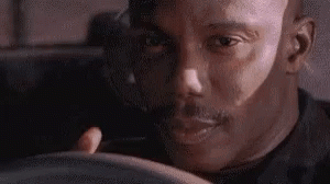 A Close Up Of A Man 'S Face While Holding A Steering Wheel . GIF