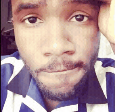 A Close Up Of A Man 'S Face With A Beard And A Blue And White Shirt . GIF