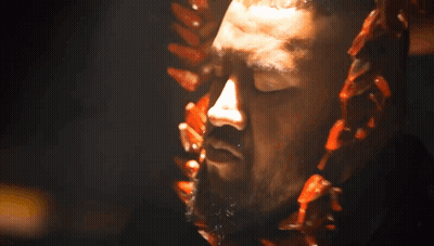 A Close Up Of A Man 'S Face With A Beard And A Necklace Around His Neck GIF