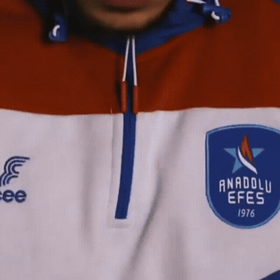 A Close Up Of A Man 'S Face With A Beard And Curly Hair Wearing A Blue And Red Jacket . GIF