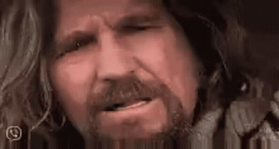 A Close Up Of A Man 'S Face With A Beard And Long Hair Making A Funny Face . GIF