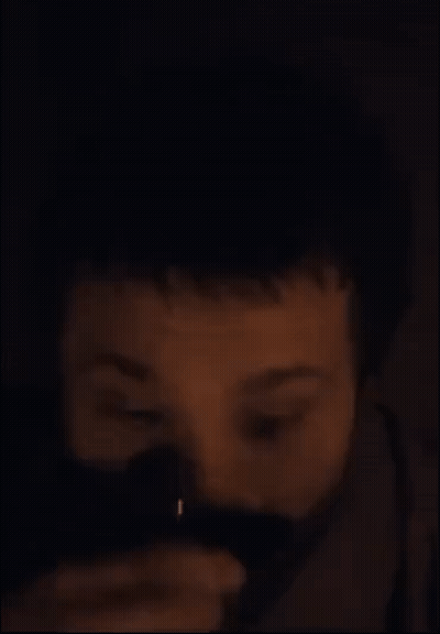 A Close Up Of A Man 'S Face With A Beard In The Dark GIF