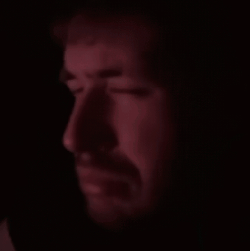 A Close Up Of A Man 'S Face With A Beard In The Dark GIF