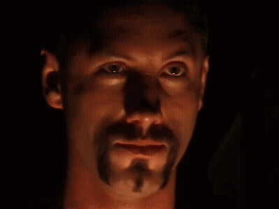 A Close Up Of A Man 'S Face With A Beard In The Dark GIF