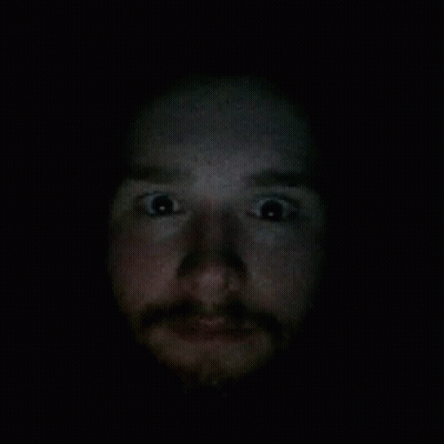 A Close Up Of A Man 'S Face With A Beard In The Dark GIF