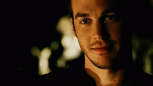 A Close Up Of A Man 'S Face With A Beard Smiling In A Dark Room . GIF