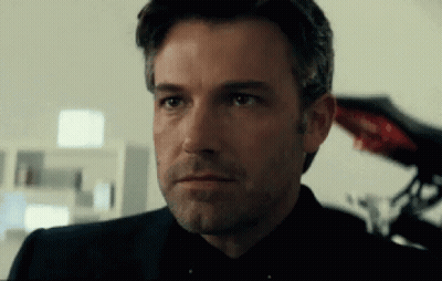 A Close Up Of A Man 'S Face With A Beard Wearing A Black Suit And Tie . GIF