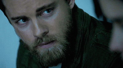 A Close Up Of A Man 'S Face With A Beard Wearing A Green Jacket GIF